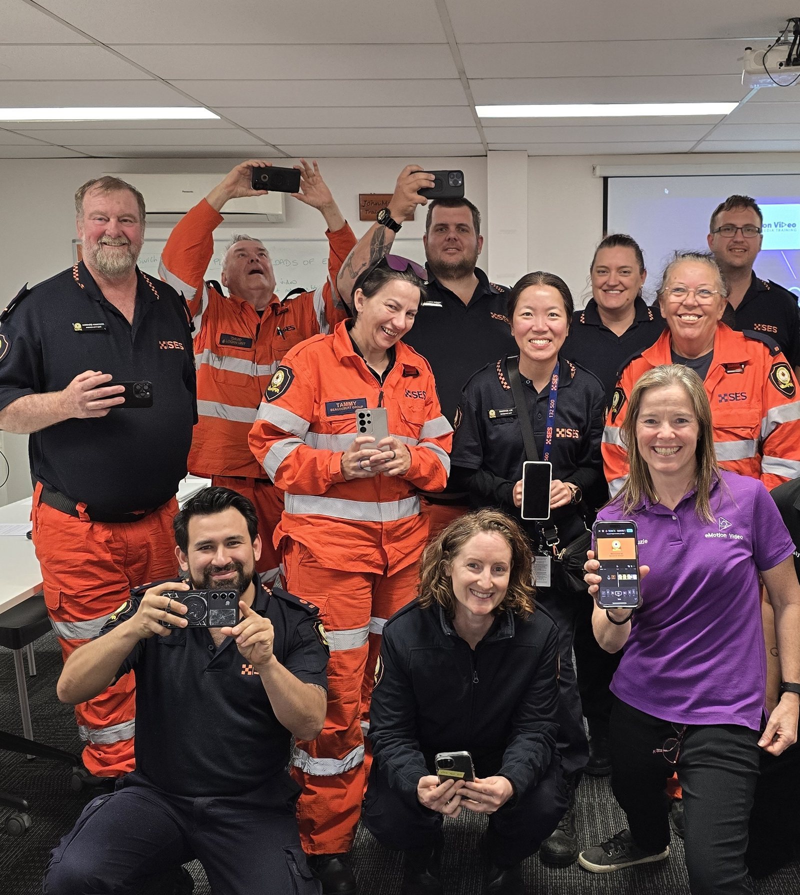 An SES team in Ipswich holding up their phones after a smartphone video training day with Suzie