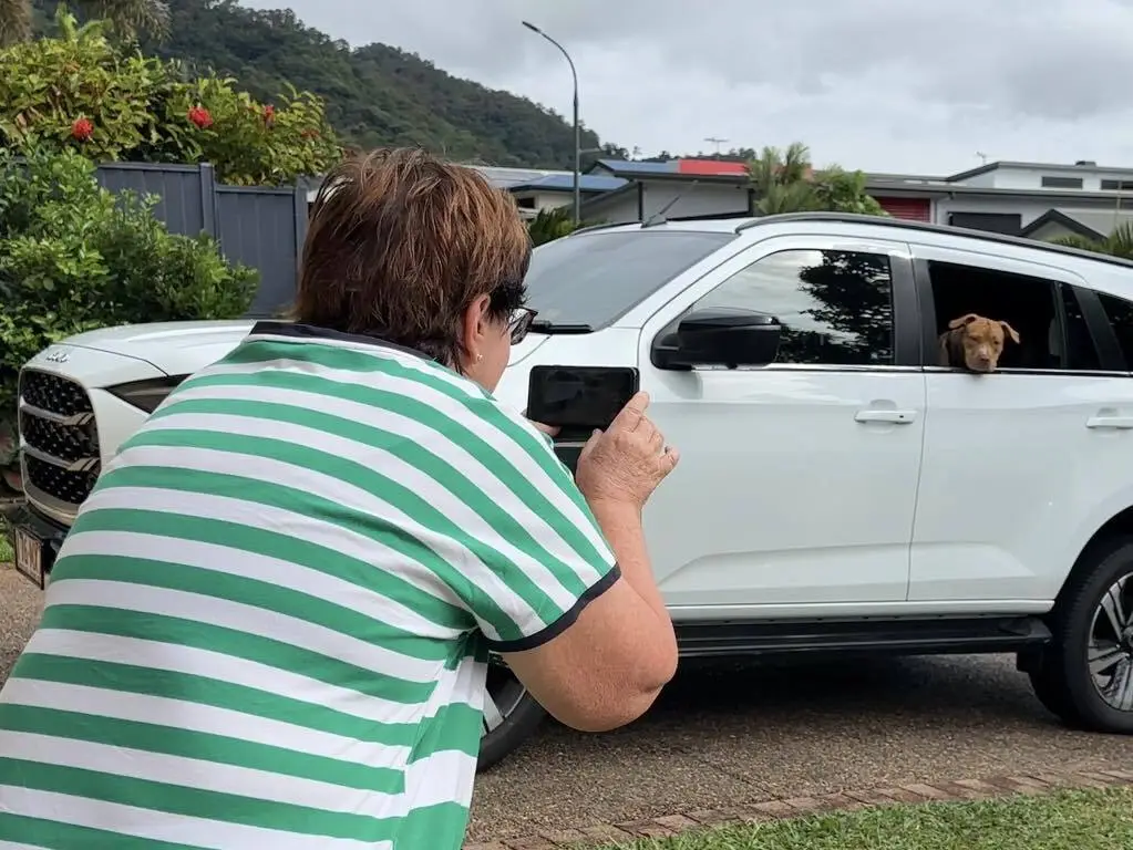 Lady taking video of a dog in a car
